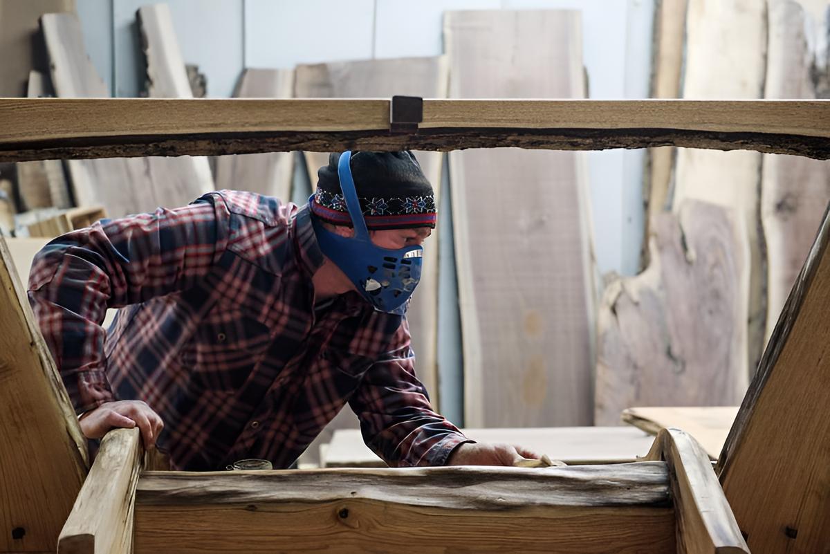 Woodworker sanding a live edge piece in front of slabs