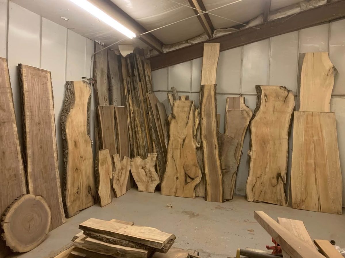 Assorted live edge hardwood slabs of different lengths and widths standing in a shop